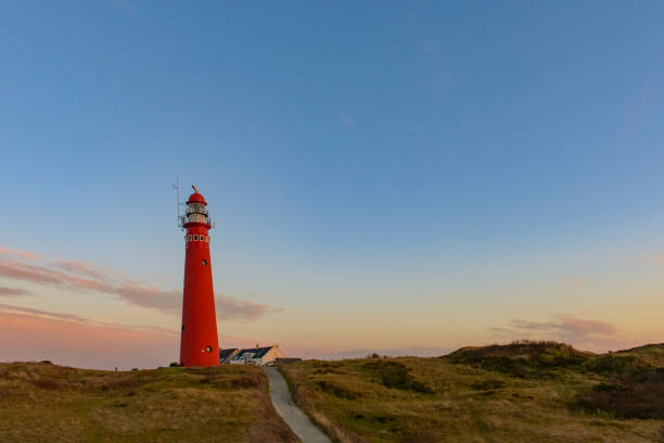 Schiermonnikoog panoramic view in the dunes with the lighthouse during sunset at the wadden island during a beautiful winter day. Schiermonnikoog is part of the Frisian Wadden Islands and is known for its beautiful natural scenery, including sandy beaches, rolling dunes, and lush wetlands.