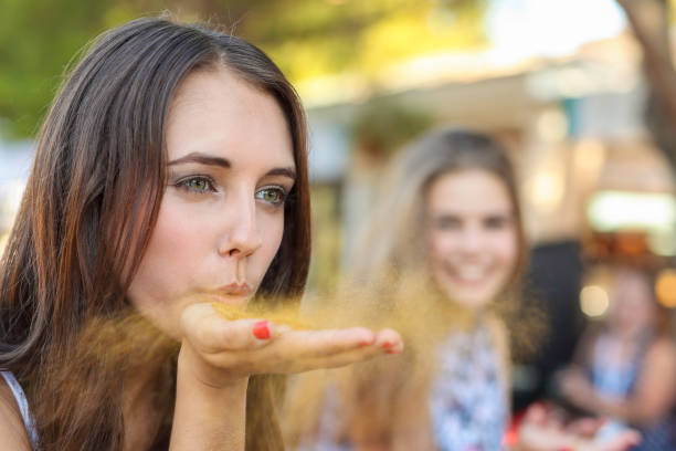 Woman blowing golden dust from her hand at a fair.