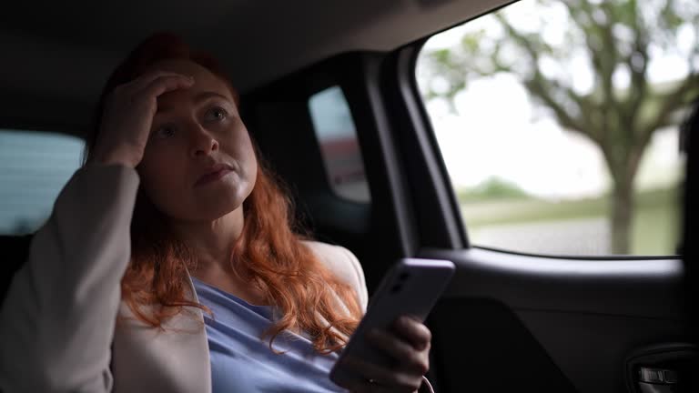 Worried mature businesswoman using the mobile phone in a car