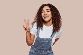 Young african curly woman does victory sign with fingers