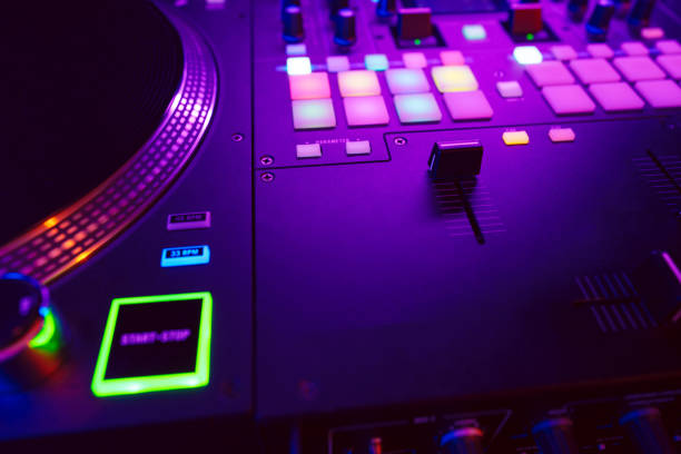 istock Close up of DJ mixing console in party light 1473667936