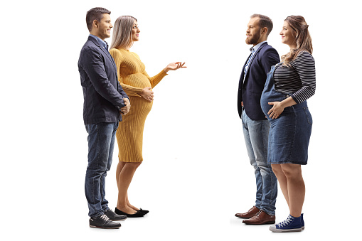 Full length profile shot of two expecting couples having a conversation isolated on white background