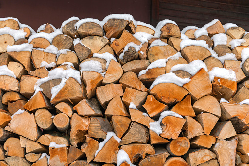 Stack of Chopped Firewood Under Snow Prepared for Winter