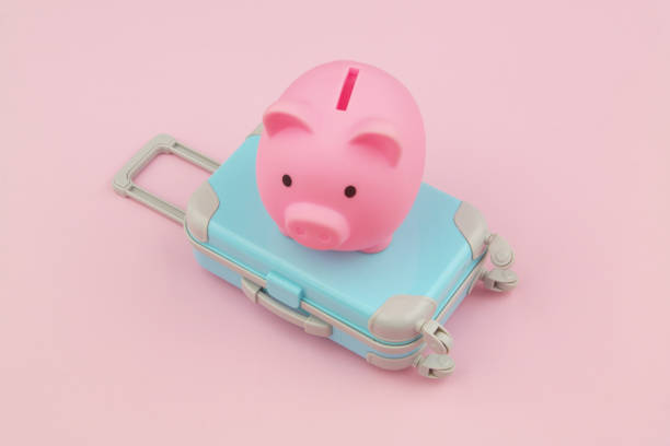 istock Piggy bank and blue suitcase on pink background. 1473671707