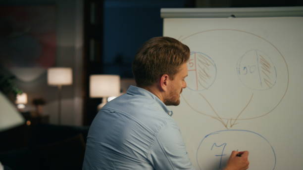 istock Casual specialist pointing whiteboard in remote workplace. Guy telling at call 1473672477