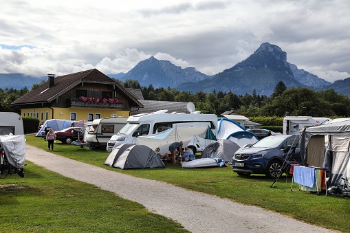 Camper vans and tents at a campground by the lake Wolfgangsee in Salzkammergut region of Austria.