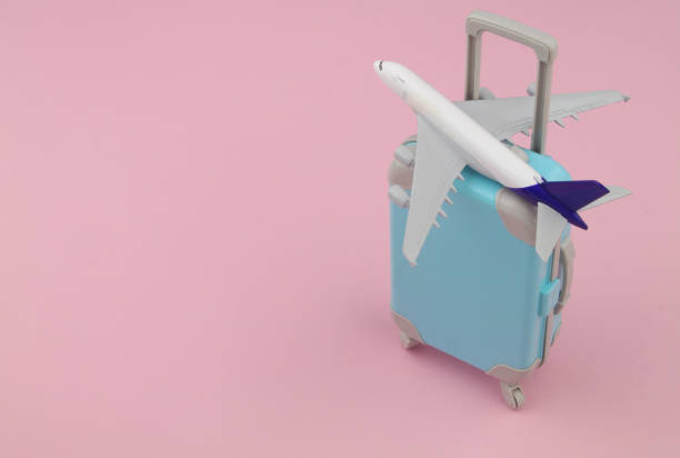 istock Airplane model with suitcase on pink background. 1473674122