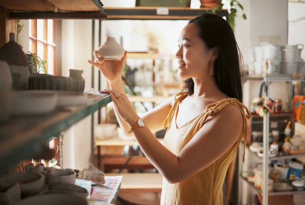 istock Pottery, small business and display with a woman entrepreneur working in a studio, selling products for retail. Startup, manager or sale with a female owner at work in a workshop for artistic design 1473674428