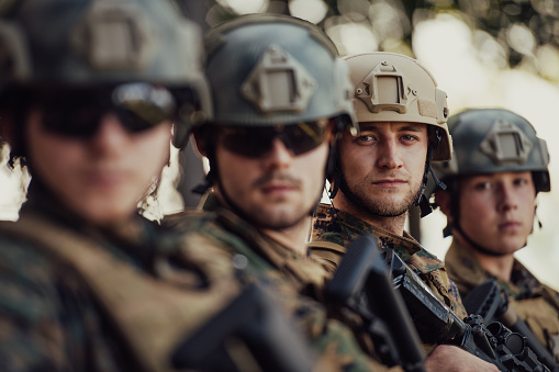 Soldier fighters standing together with guns. Group portrait of US army elite members, private military company servicemen, anti terrorist squad.