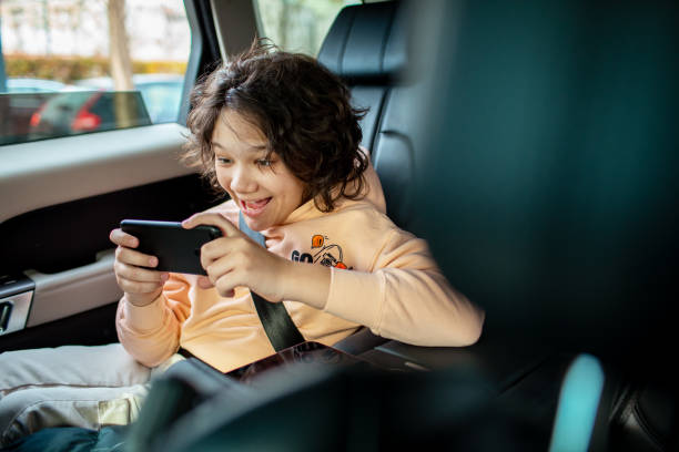 istock Little boy using a smart phone in a backseat of a car 1473676126
