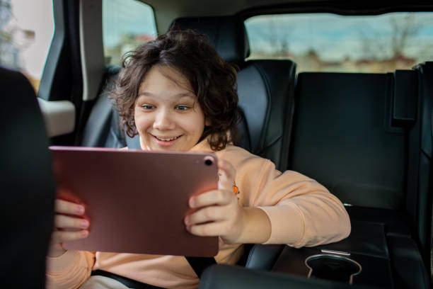 istock Little boy using a digital tablet in a backseat of a car 1473676129