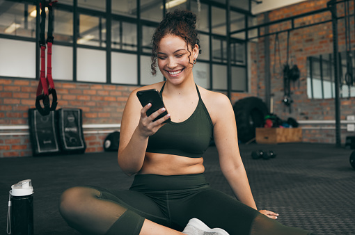 Happy woman, fitness and phone at gym for a workout, training and body wellness with a mobile app. Sports female with smartphone for progress, performance and communication for a healthy lifestyle