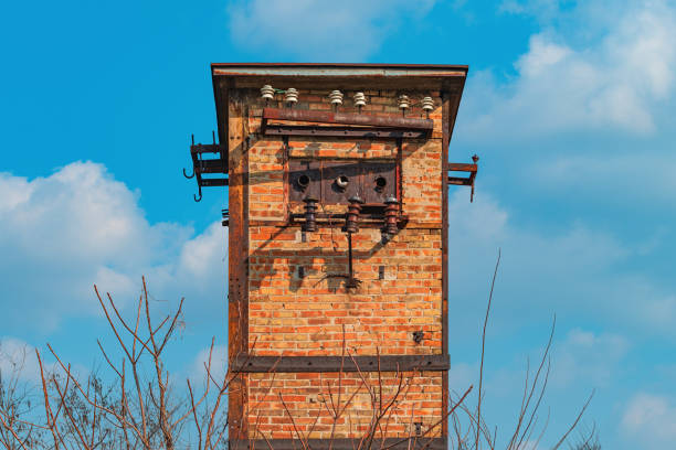 Old worn abandoned electricity cabin tower made of bricks, against blue sky