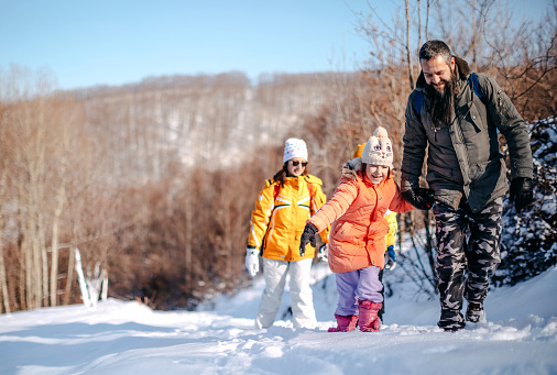 Family with two kids walking on snow in nature