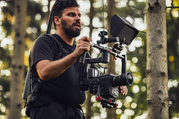 istock Videographer with Professional Movie Video Camera Gimbal Stabilizing Equipment Taking Action Shoot of Soldiers in Action in Forest 1473682572