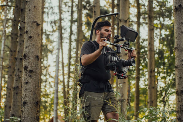istock Videographer with Professional Movie Video Camera Gimbal Stabilizing Equipment Taking Action Shoot of Soldiers in Action in Forest 1473682654