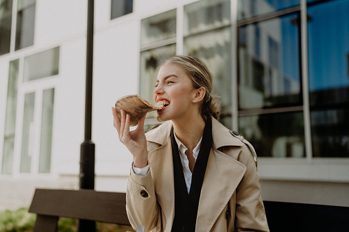 Young woman eating pizza slice outdoors