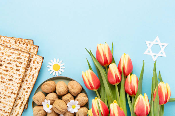 istock Passover greeting card with matzah, nuts daisy and tulip flowers on blue background. 1473683155