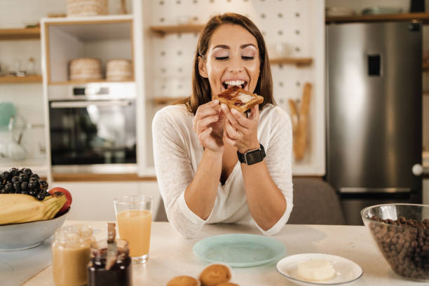 frau genießt das frühstück zu hause - toast preserves breakfast bread stock-fotos und bilder