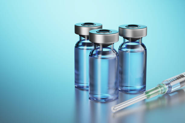 A disposable syringe is filled with a clear liquid and lies on a metal table. Disposable syringe with three glass vials of medicines. 3d render. stock photo