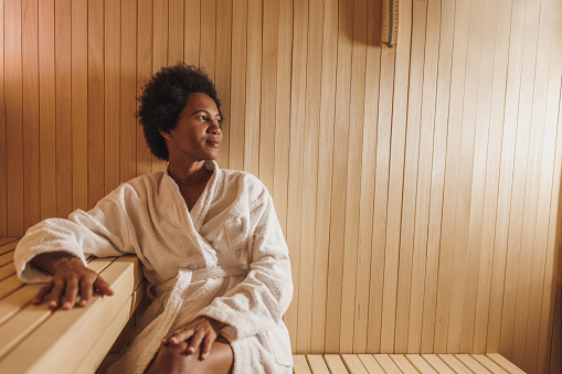 Beautiful mature African American woman relaxing in a sauna at the spa centre.