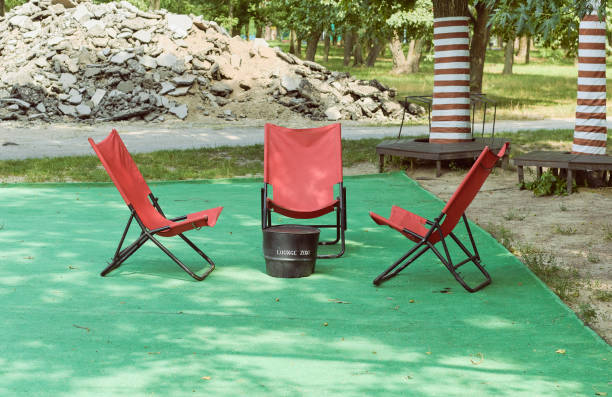 Three red sunbeds in the park. Construction waste on the background.