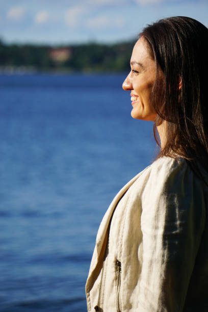 istock Smiling woman standing by lake against sky during sunset 1473687848