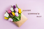 beautiful spring composition for Mother's Day. multi-colored tulips in a craft envelope. top view. flat layout. text wooden letters.