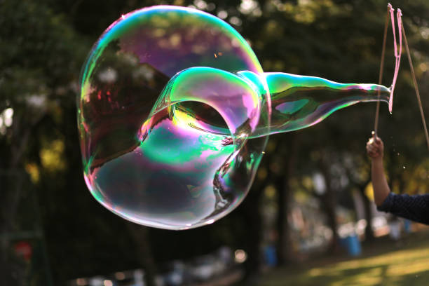 istock Playing With Huge Bubble Against Trees At Park 1473689565