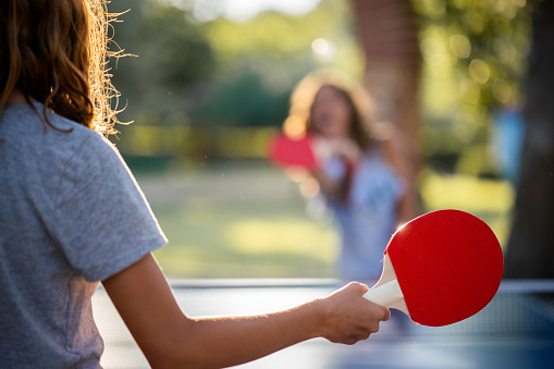 Close-up of happy girls playing table tennis on summer day