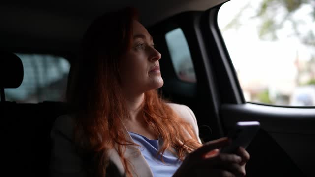 Businesswoman using the mobile phone in a car