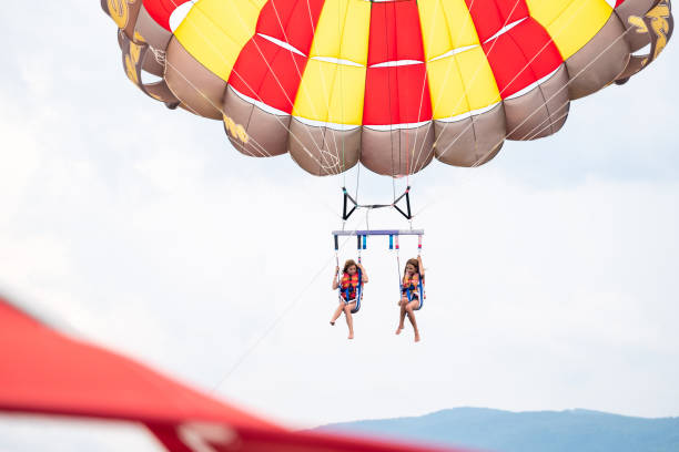 Girls parasailing during summer day at sea Happy girls parasailing during summer day at sea parasailing stock pictures, royalty-free photos & images