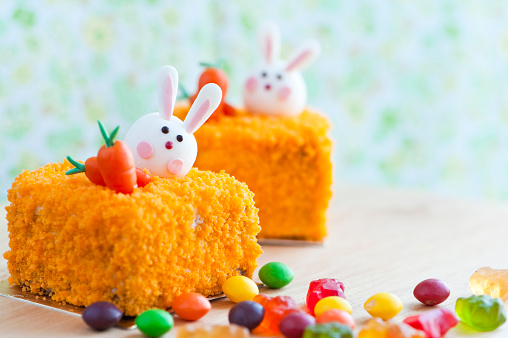 Carrot cheese cakes ready for easter. Colorful decorated easter table with Easter cakes and candies. Close up of carrot cheese cake square. Selective focus.