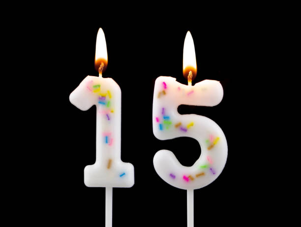 istock Burning birthday candles isolated on black background, number 15 1473693785