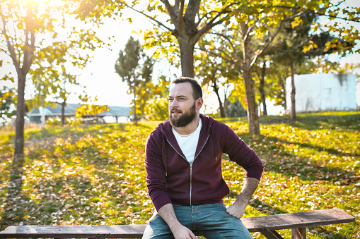 Bearded Male Sitting On Park Bench During Morning And Relaxing