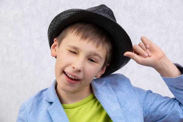 Portrait of a handsome cheerful winking boy in a hat.