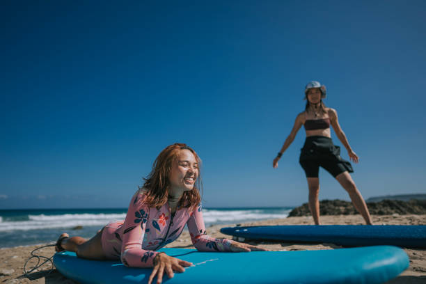 istock female Asian Chinese wave surfer practising on beach before heading to sea wave surfing 1473700321