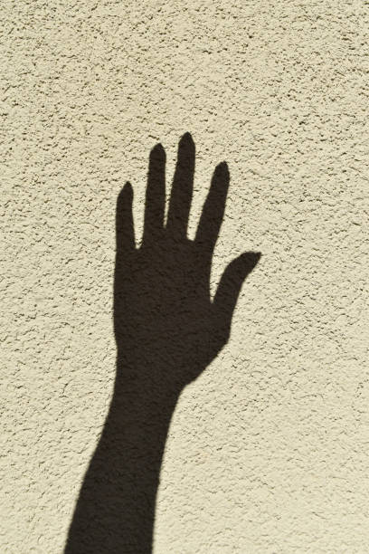 istock the shadow of a hand on the rough wall. 1473701274
