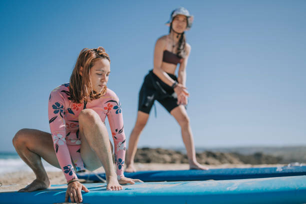 2 Asian Chinese wave surfing female student practicing on beach