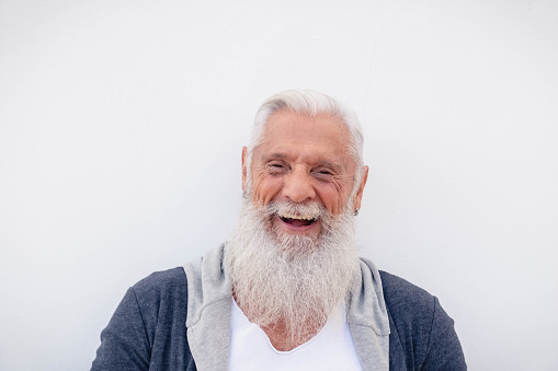 Happy hipster senior man smiling on camera with green background - Focus on face
