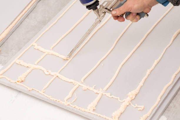 istock Foam gun applying gluing foam on styrofoam for warming building 1473704230