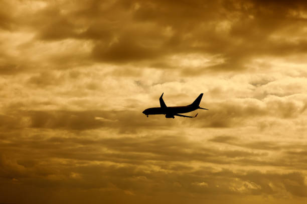 Airplane silhouette ready to land, Orange sunset clouds background