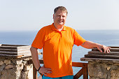 A man in a yellow orange t-shirt on a bright sunny day