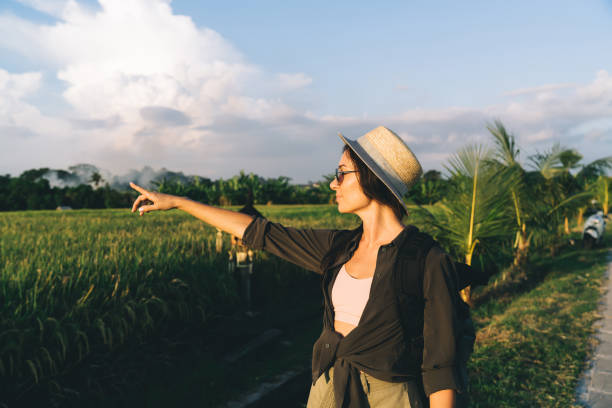 istock Young woman walking on path near green rice field 1473706092