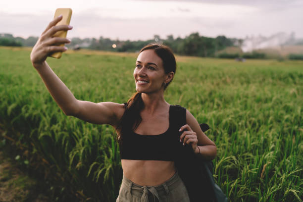 istock Young muscular woman walking through field and taking selfie 1473706155