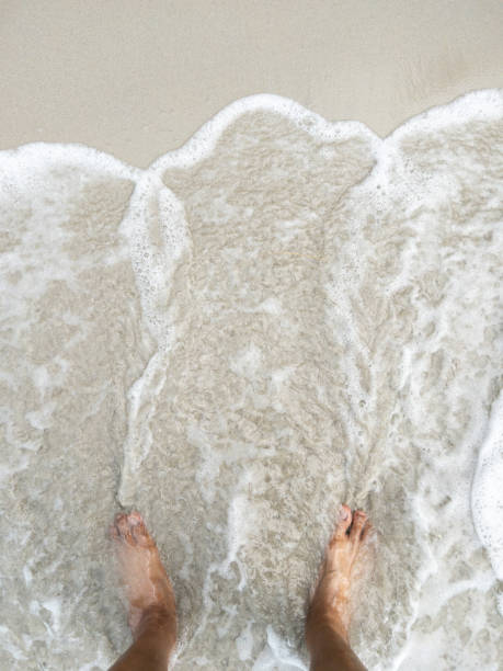 istock The barefoot on the beach with the white foam from the wave. 1473706361