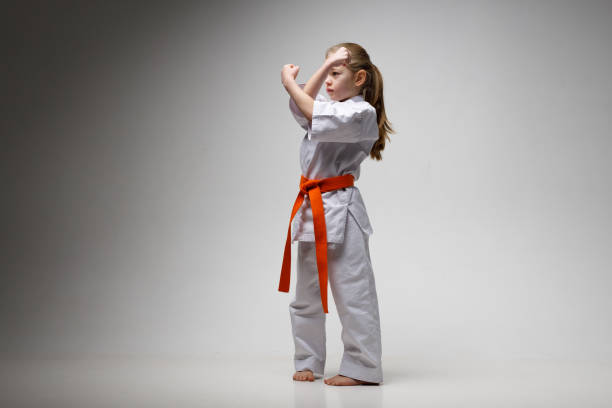 istock Blocking punches karate, child girl trains on a white background. 1473706382