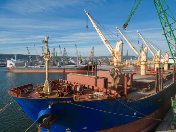 istock A bulk carrier ship loaded with grain is docked at a busy port, with workers and machinery seen in the background. 1473706395