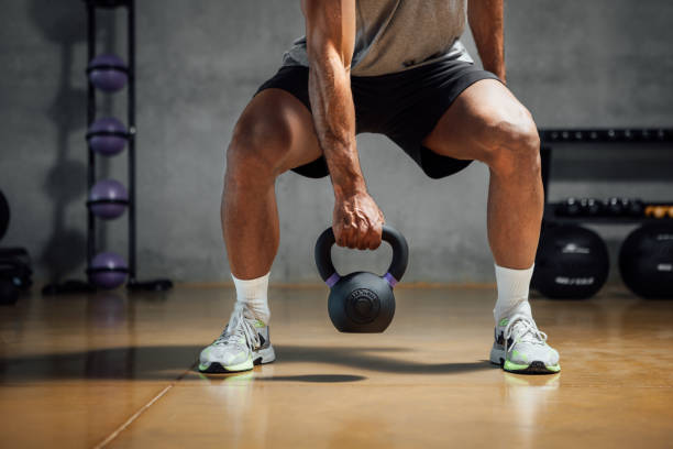 istock Athletic man lifting weight with kettle bell in gym. 1473707077