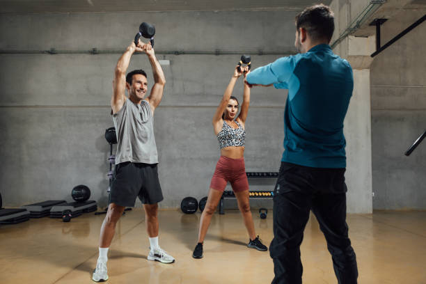 istock Fitness instructor giving kettle bell class in dark shadow gym 1473707089